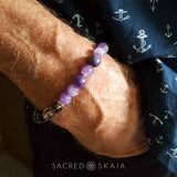 Crystal bracelet with clasp in custom sizes, shown on a man's wrist, for supporting your intention to be free from addiction, made with amethyst, hematite, smoky quartz, black obsidian, lepidolite and rosewood. Includes a silver cross accent and silver spacers.