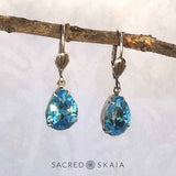 Vintage-style Aphrodite Crystal Teardrop Earrings with oxidized silver settings, lever back ear wires and pear-shaped aquamarine Swarovski crystals, shown hanging on a branch