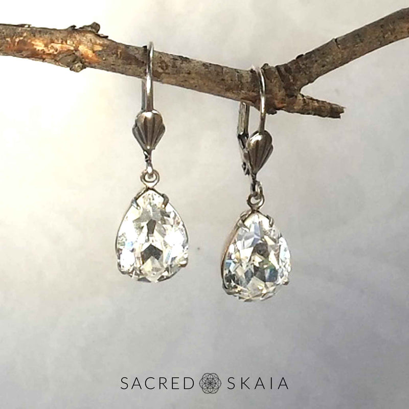 Aphrodite Crystal Teardrop Earrings with oxidized silver settings, lever back ear wires and pear-shaped clear Swarovski crystals, shown hanging on a branch as an alternate color choice