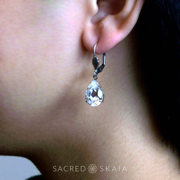 Aphrodite Crystal Teardrop Earrings with oxidized silver settings, lever back ear wires and pear-shaped clear Swarovski crystals, shown on a model with pierced ears