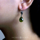 Aphrodite Crystal Teardrop Earrings with oxidized silver settings, lever back ear wires and pear-shaped olivine (dark olive green) Swarovski crystals, shown on a model with pierced ears