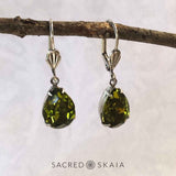 Vintage-style Aphrodite Crystal Teardrop Earrings with oxidized silver settings, lever back ear wires and pear-shaped olivine (dark olive green) Swarovski crystals, shown hanging on a branch
