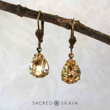 Aphrodite Crystal Teardrop Earrings with oxidized brass settings, lever back ear wires and pear-shaped light silk (pale golden) Swarovski crystals, shown hanging on a branch as an alternate color choice